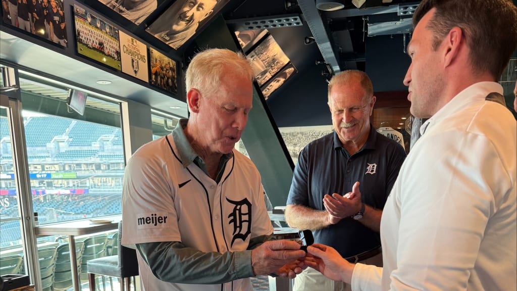 Randy O'Neal accepts his 1984 World Series ring from Ilitch Sports + Entertainment president Ryan Gustafson as O'Neal's 1984 Tigers teammate Dan Petry looks on.
