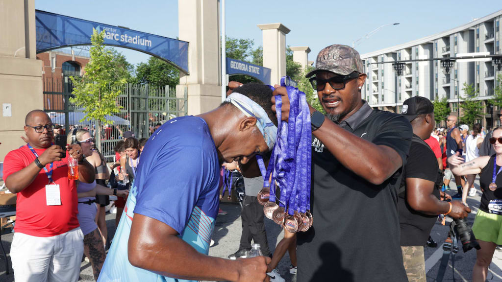 Adam Jones gives a medal to a runner during the 2025 MLB All-Star 4.4 Miler at Center Parc Stadium on Sunday, July 13, in Atlanta.