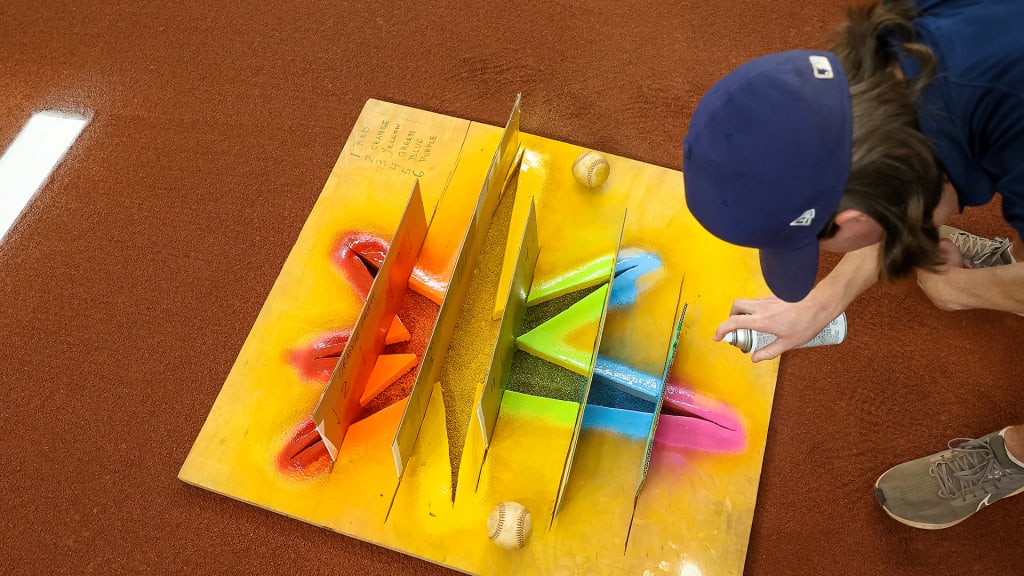 A groundskeeper finishes painting a Rays logo in Pride colors prior to the Rays' Pride Night game vs. the Rangers