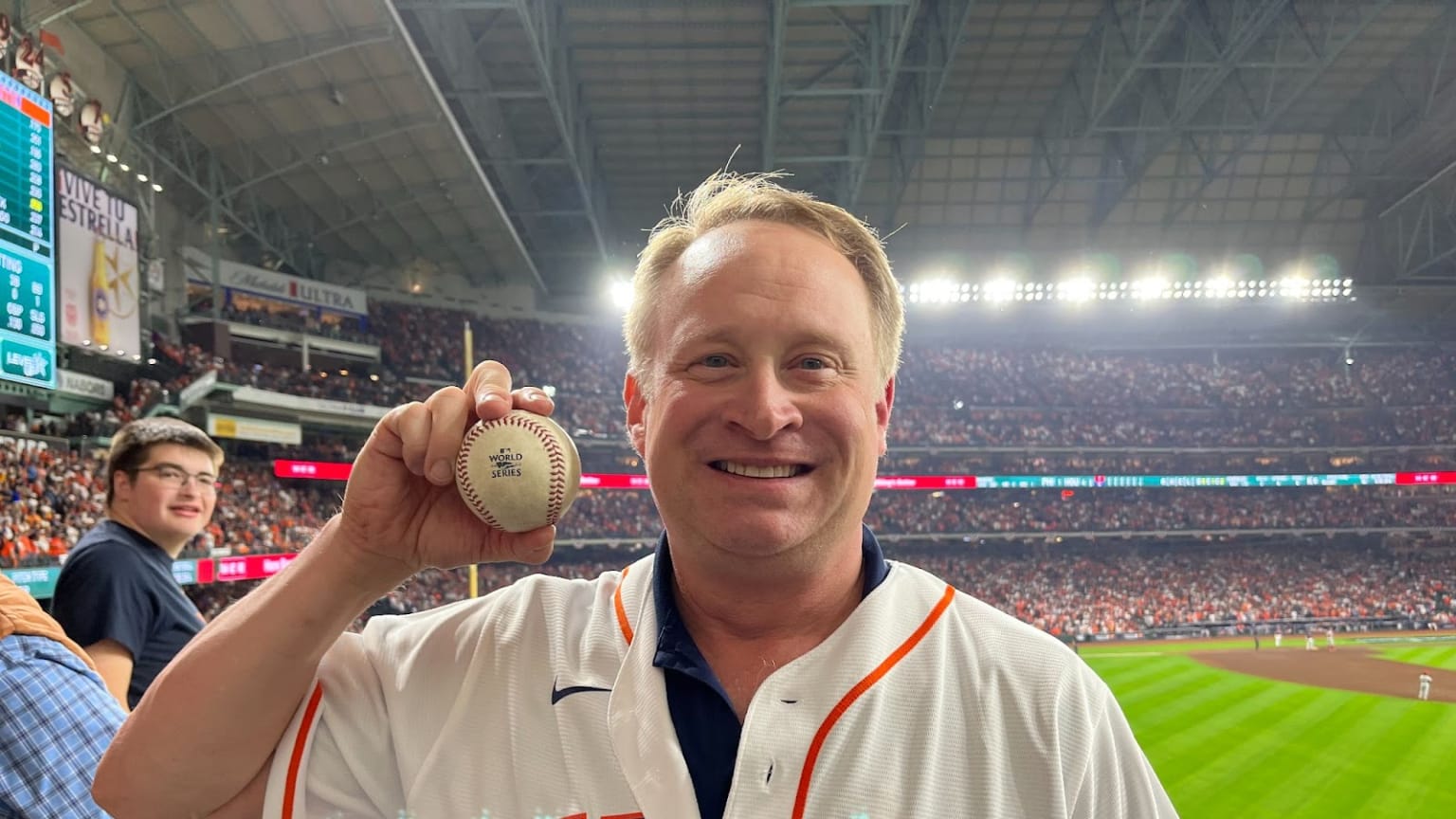 A smiling fan holds up a baseball