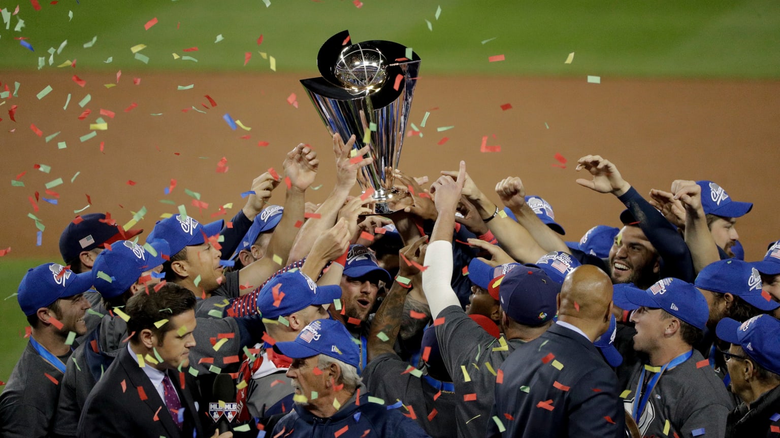 Players hold up a trophy as confetti falls around them