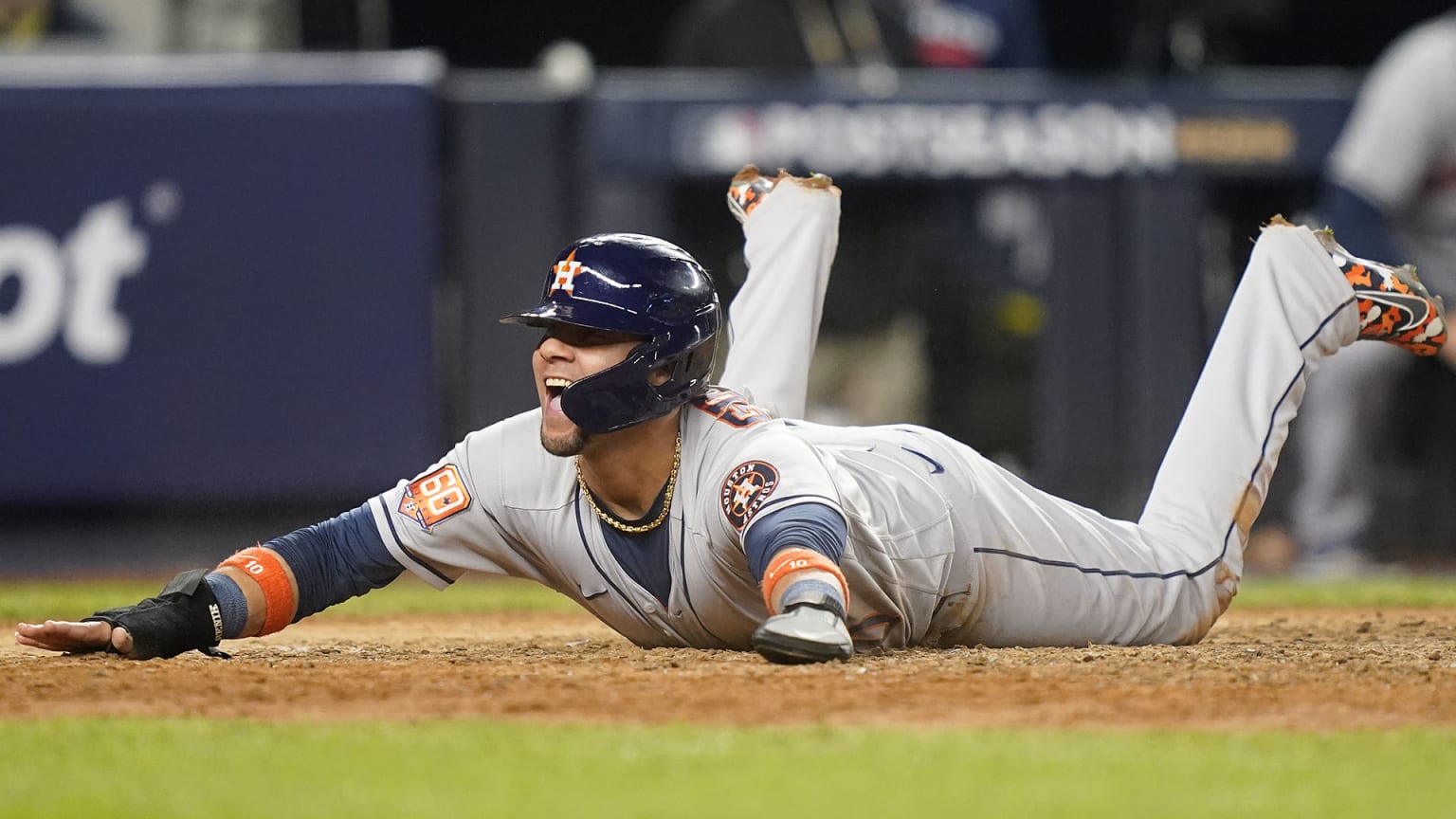 An Astros player is happily splayed out on his stomach after sliding home to score a run