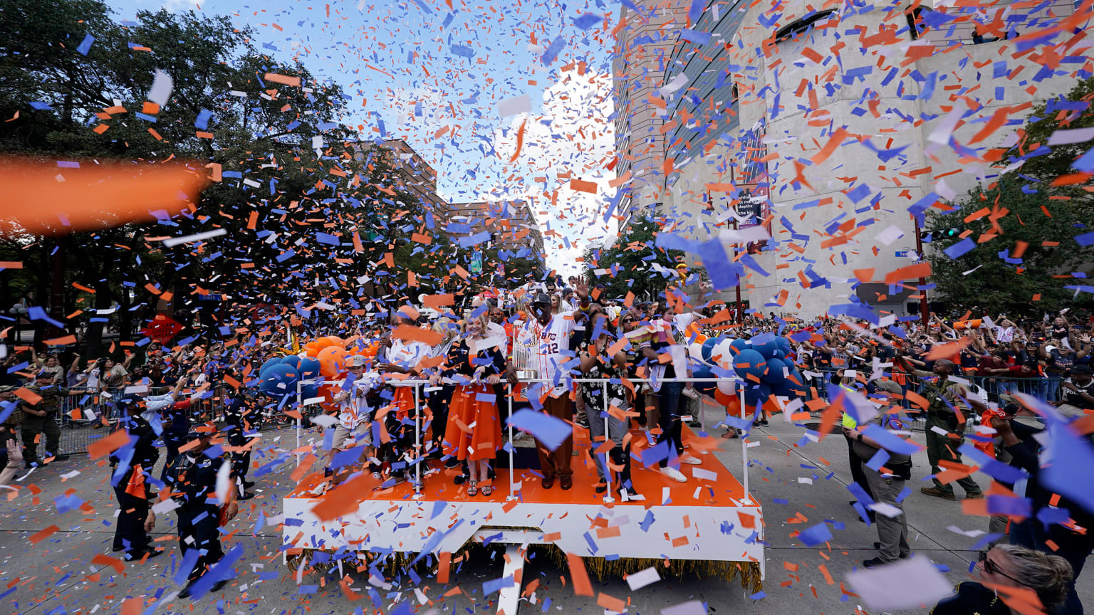 A parade float is seen through blue and orange confetti falling from nearby buildings