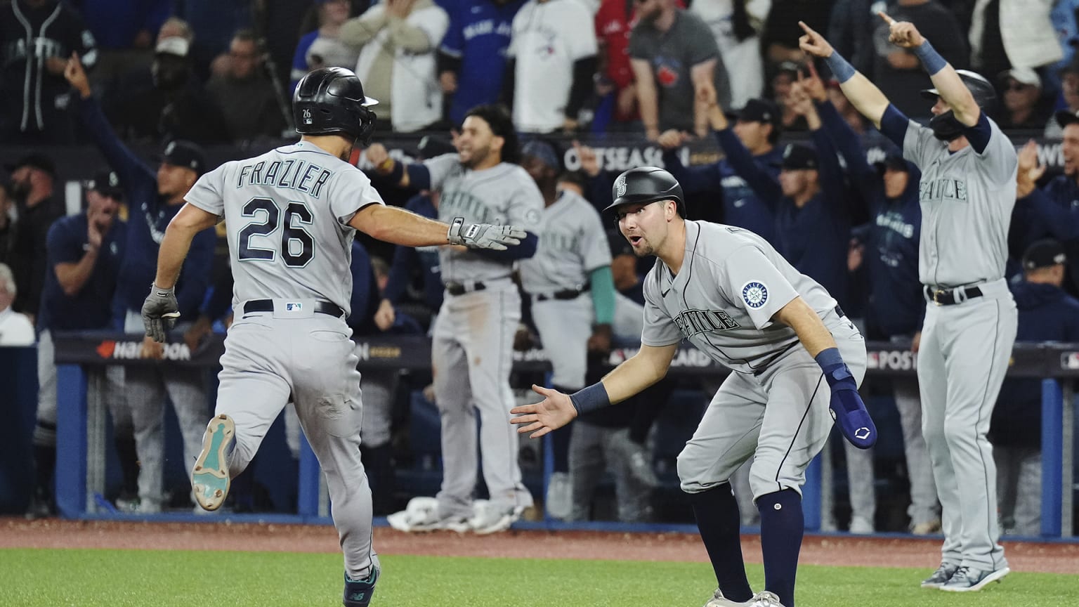 Two Mariners players prepare to low-five after one scores a run, while two others celebrate in the background