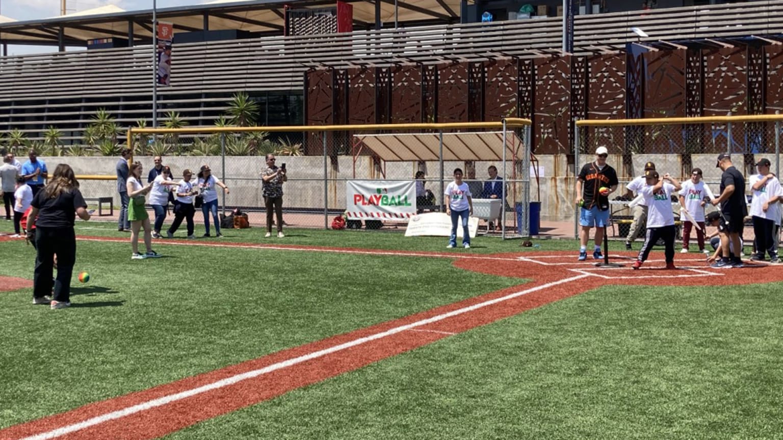 A Giants player stands near home plate while a child bats