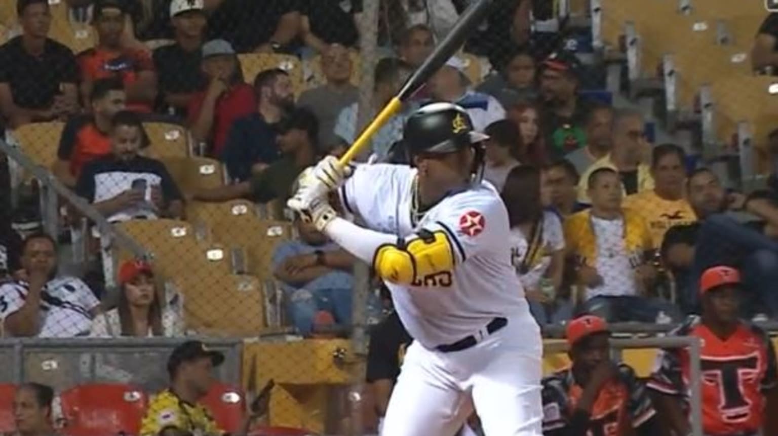 Yoenis Cespedes at bat in a white uniform in front of fans in yellow seats