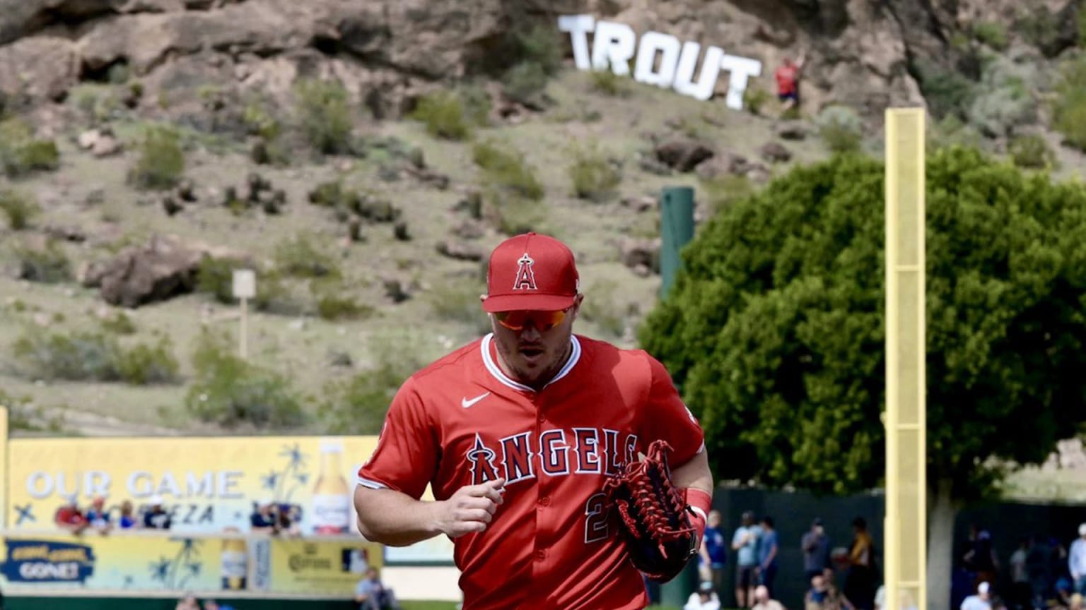 Mike Trout jogs off the field, with huge letters spelling out his last name in the hills beyond the ballpark