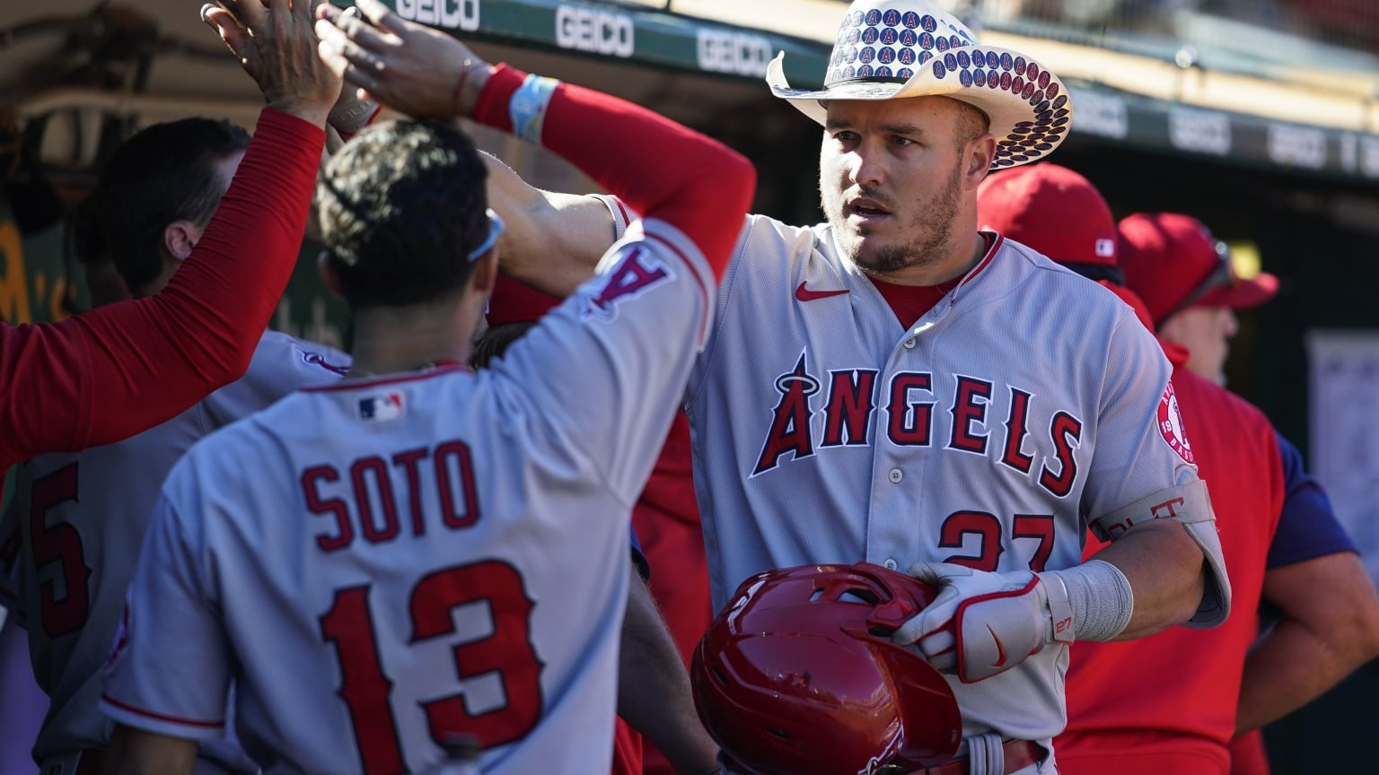 Mike Trout wears a cowboy hat and receives high-fives in the Angels dugout