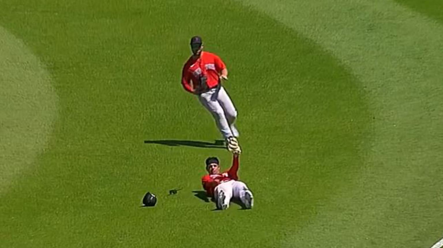 A player lying on the ground holds up his arm as another player jogs in