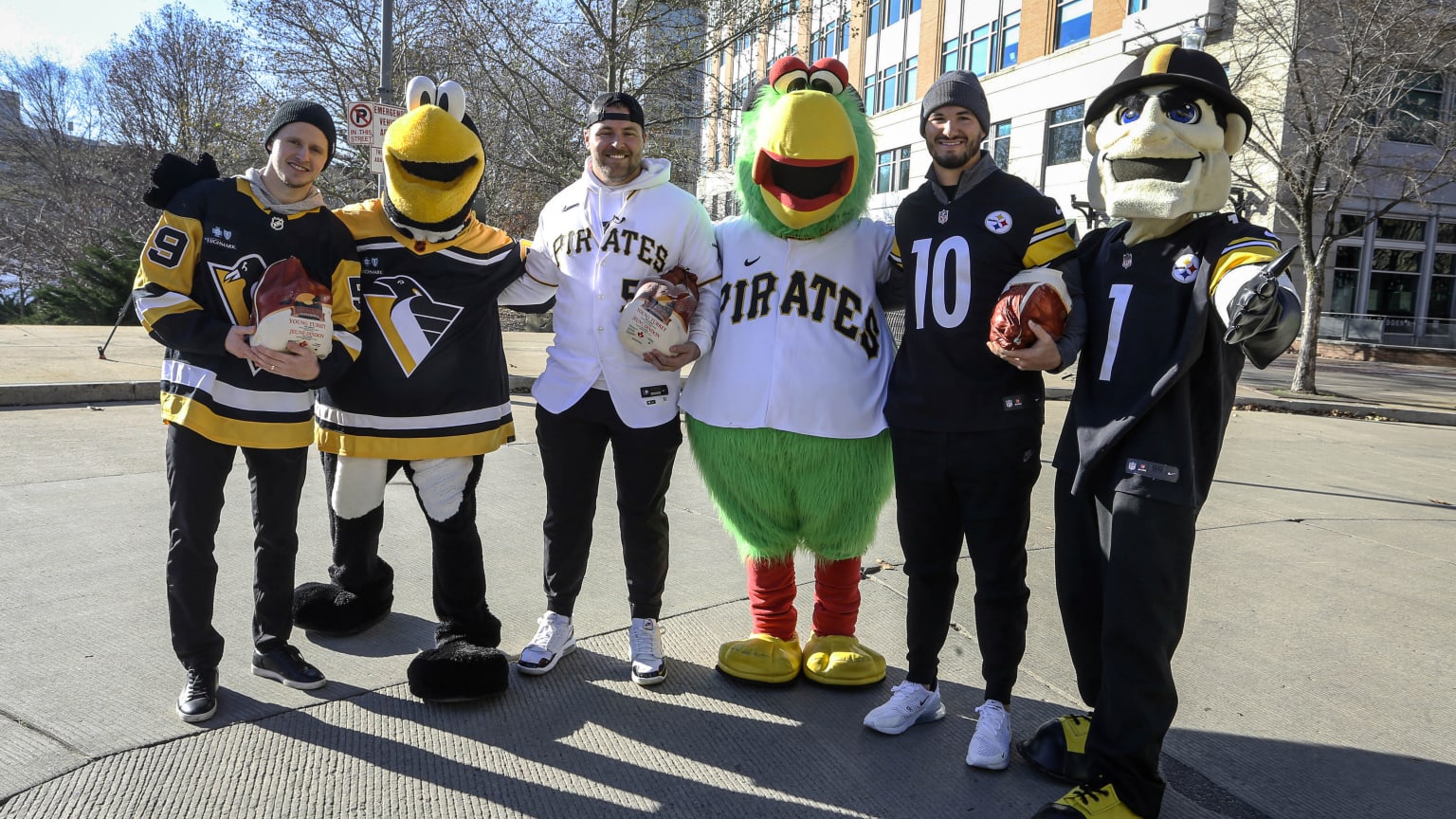 A Pittsburgh Penguins player, the Penguins mascot, a Pirates player, the Pirates mascot, a Steelers player and the Steelers mascot pose for a photo