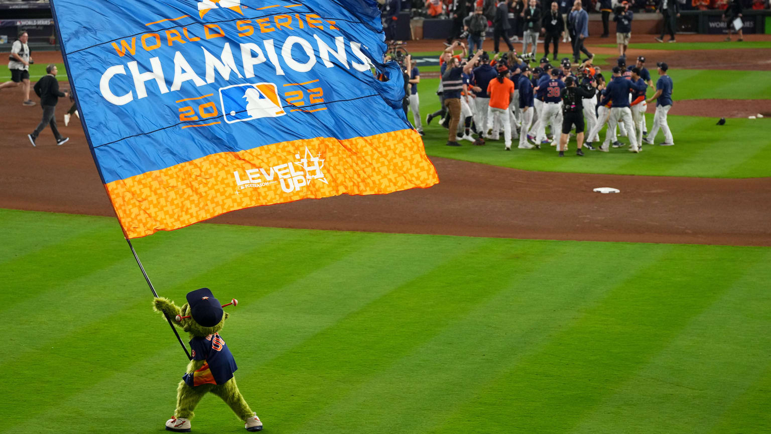 Astros mascot Orbit waves a World Series champions flag in the outfield as the team celebrates in the infield