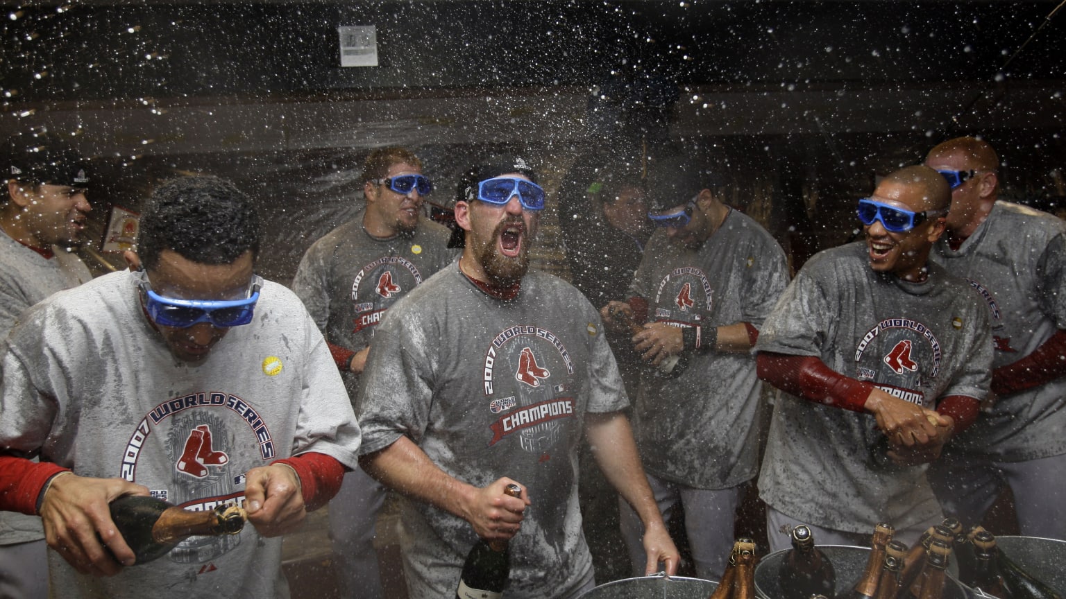 Red Sox players celebrate in gray T-shirts as champagne sprays