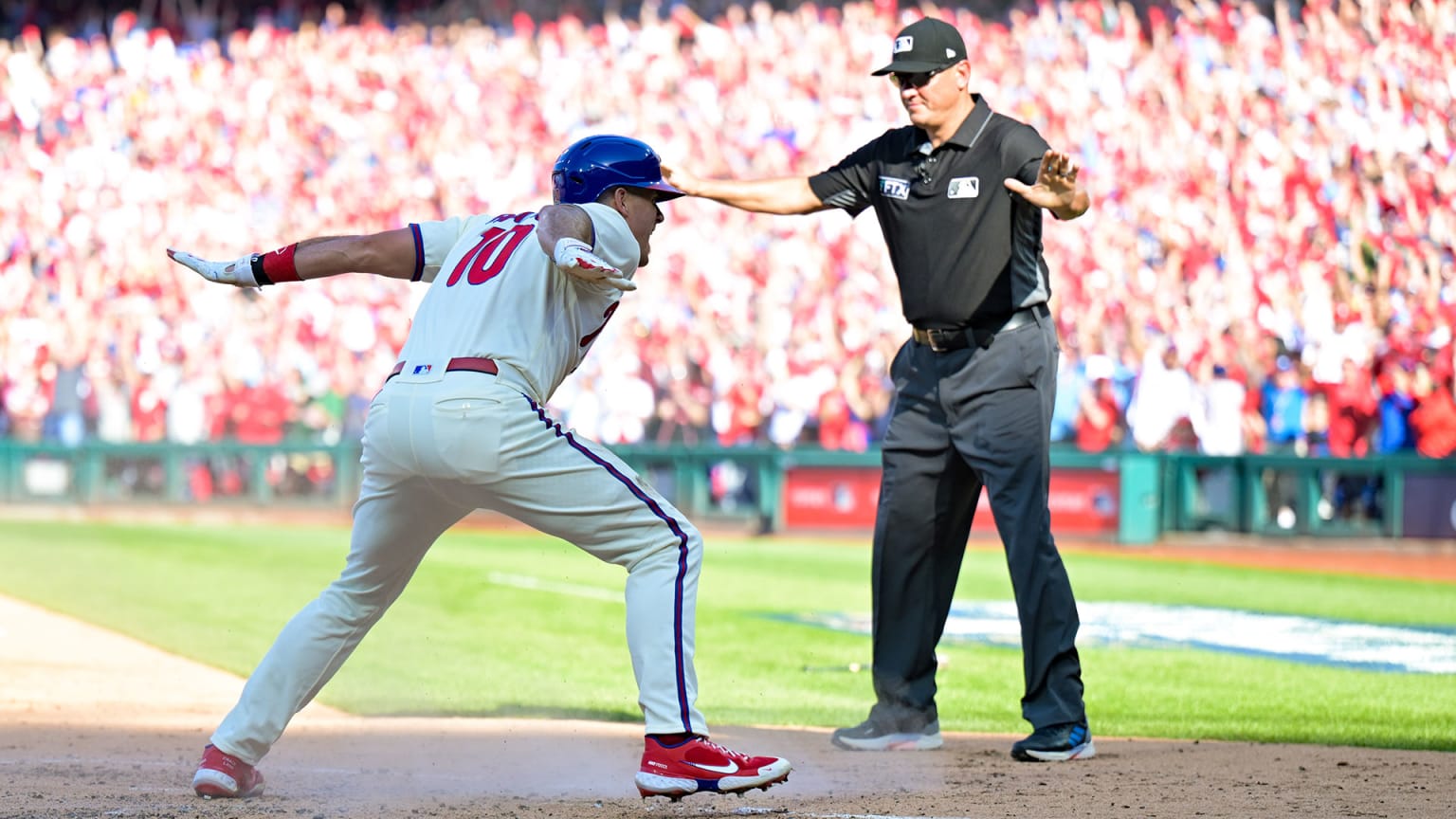 A Phillies player celebrates by giving the ''safe'' sign at home plate just as the umpire next to him does the same