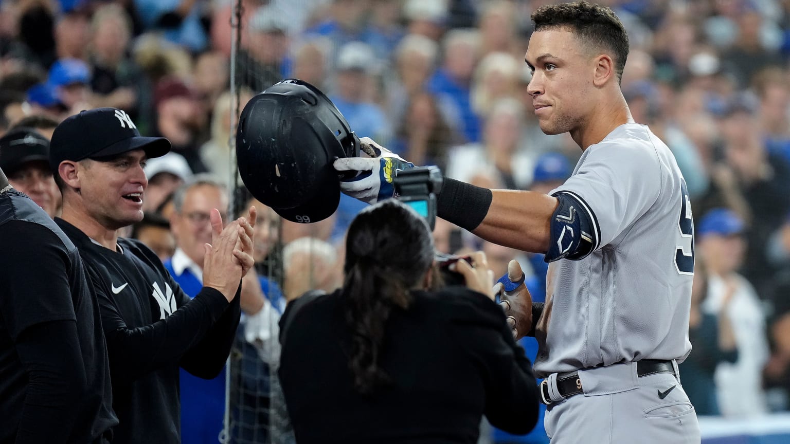 Aaron Judge tips his helmet toward the crowd as he stands in front of the Yankees dugout in Toronto after hitting his 61st home run