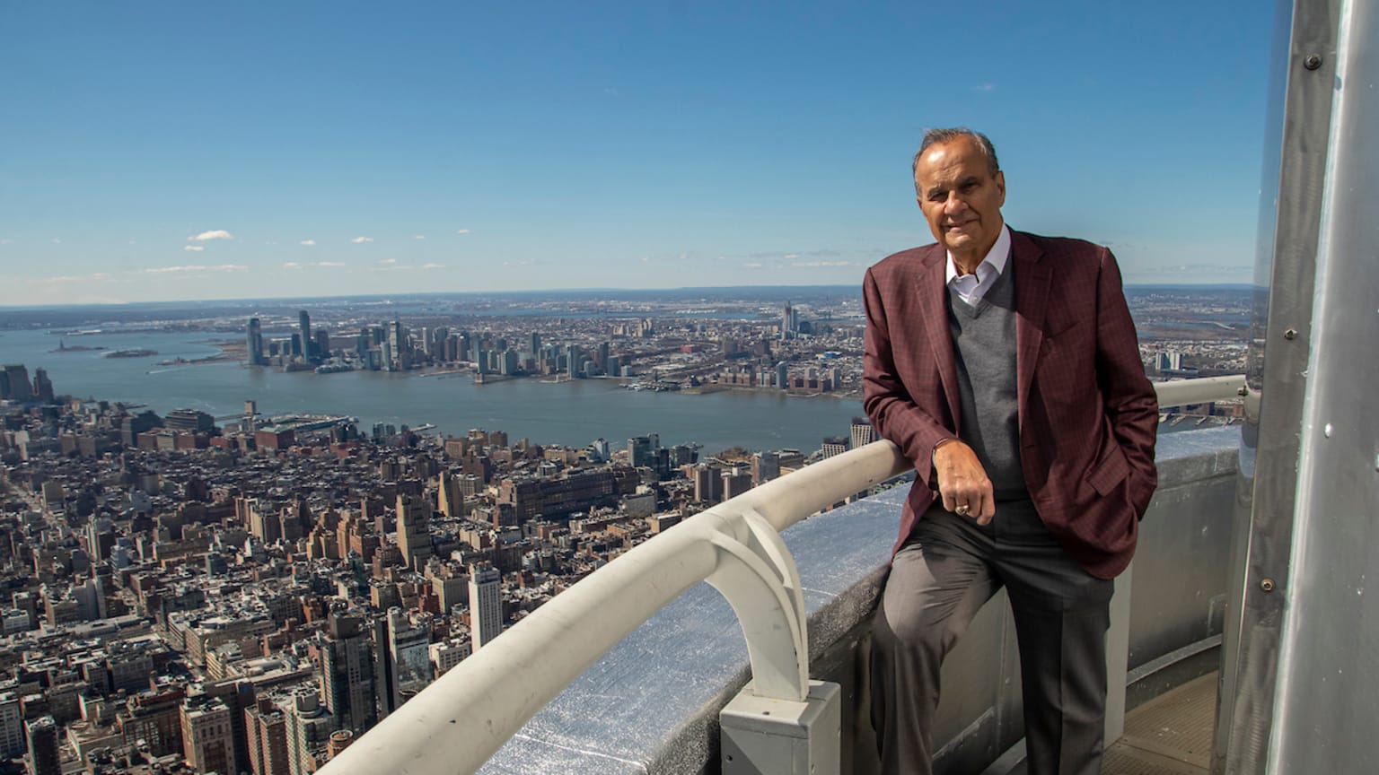 A man stands by the railing of an observation deck high above New York City