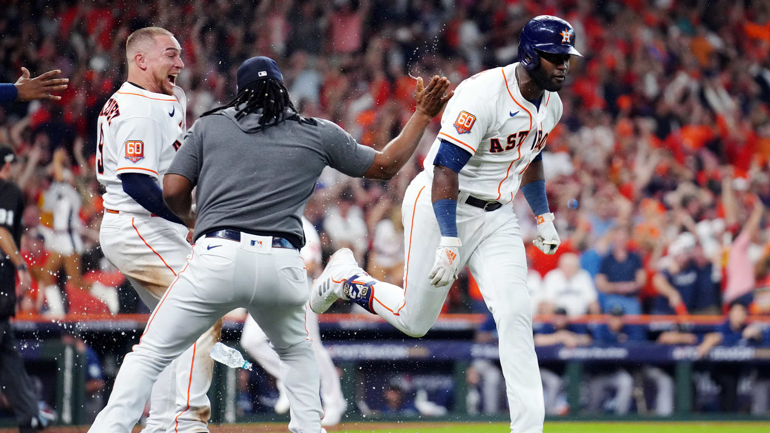 An Astros player runs past two teammates who are celebrating