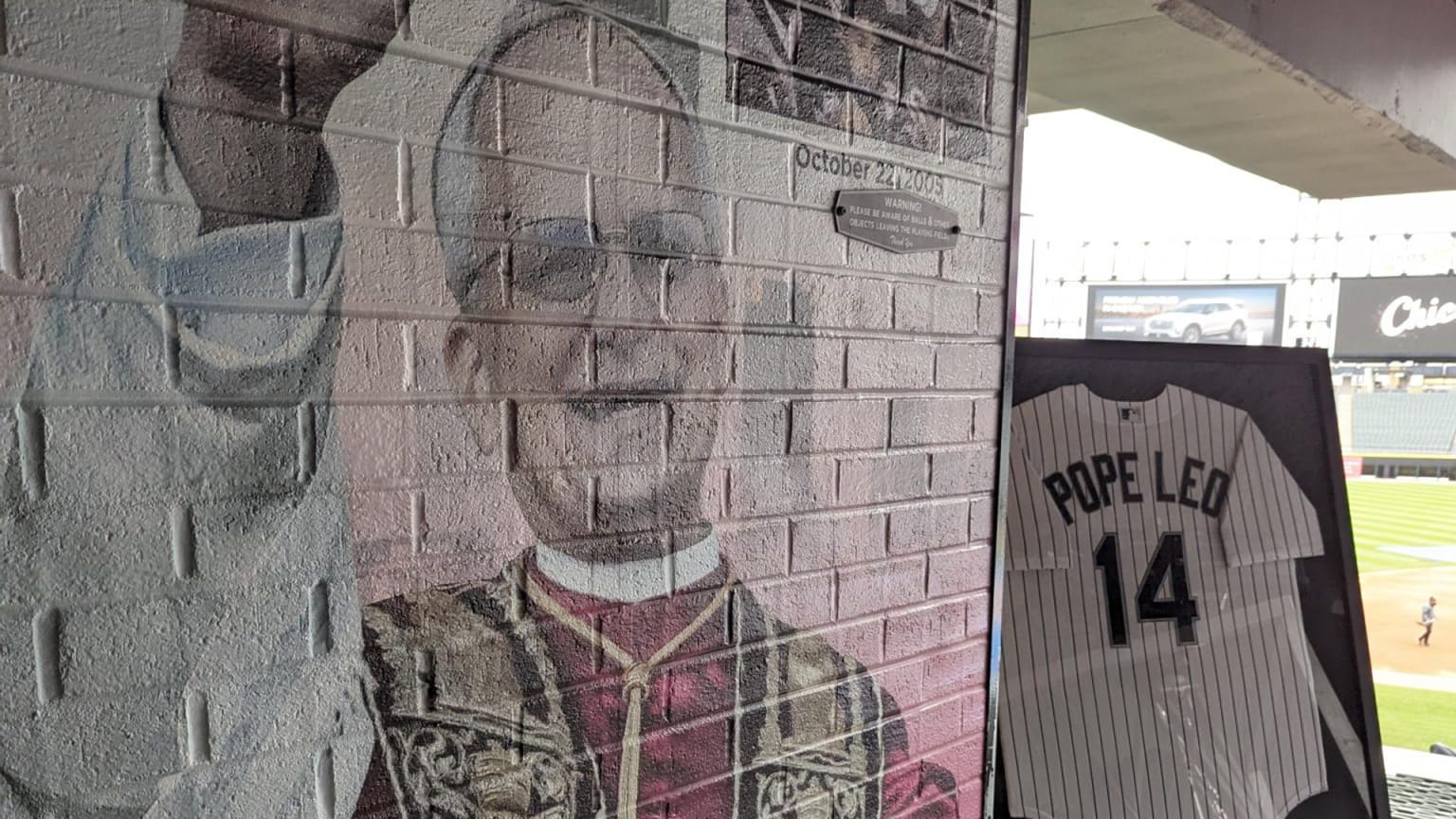 A mural of Pope Leo XIV on a brick wall and a White Sox jersey with his name on the back above the number 14