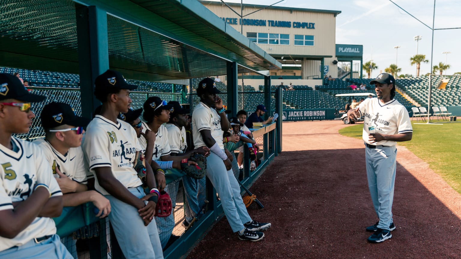 Players gather in a dugout during the Hank Aaron Invitational