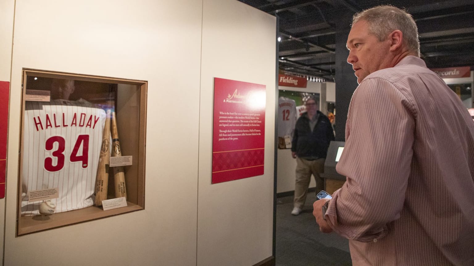 Scott Rolen looks at a Roy Halladay jersey in the Hall of Fame