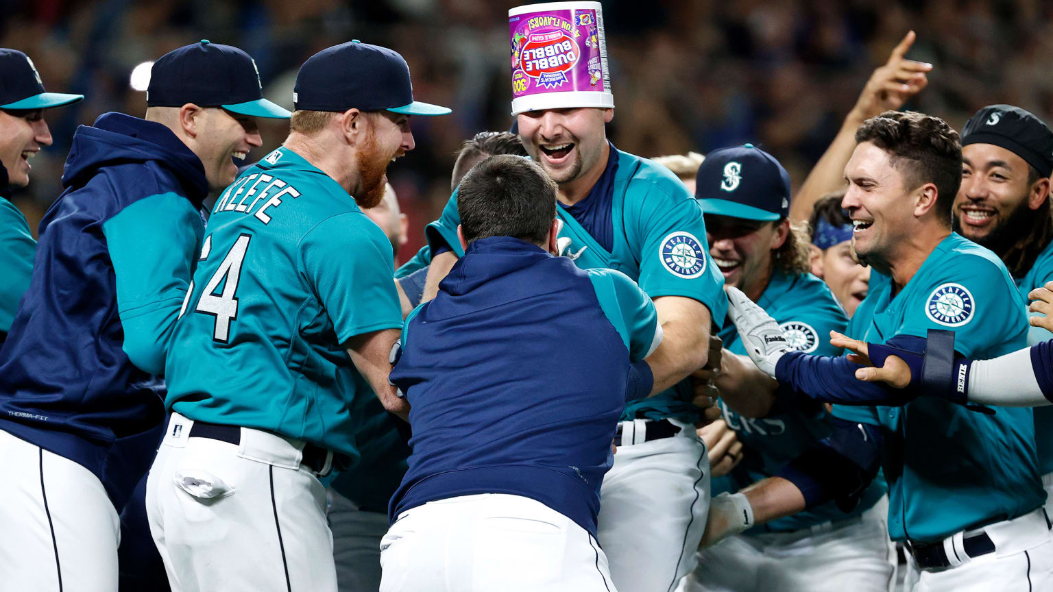 Seattle Mariners celebrate a walk-off home run. A player at center wears a bubble-gum bucket on his head