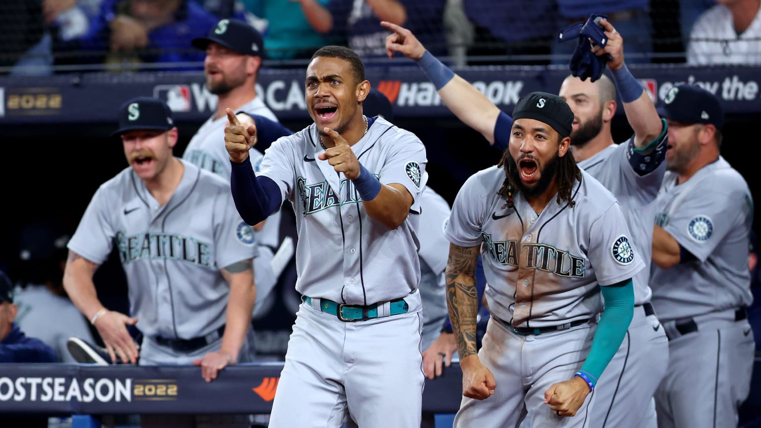 Several Mariners players step out of the dugout in celebration