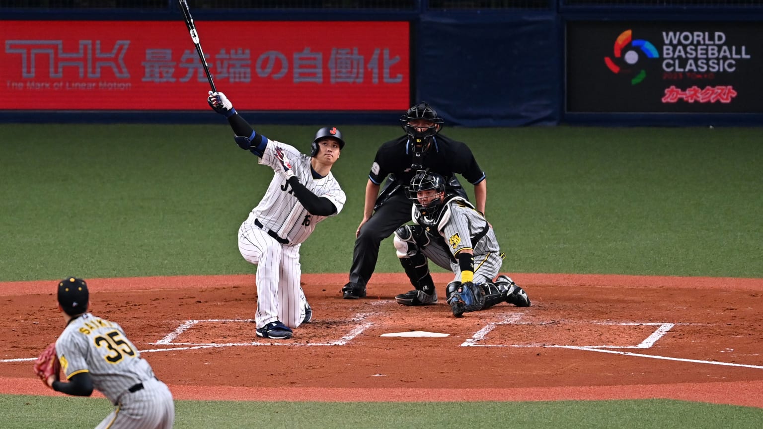 A view from the outfield of a batter following through on a home run with his knee on the ground