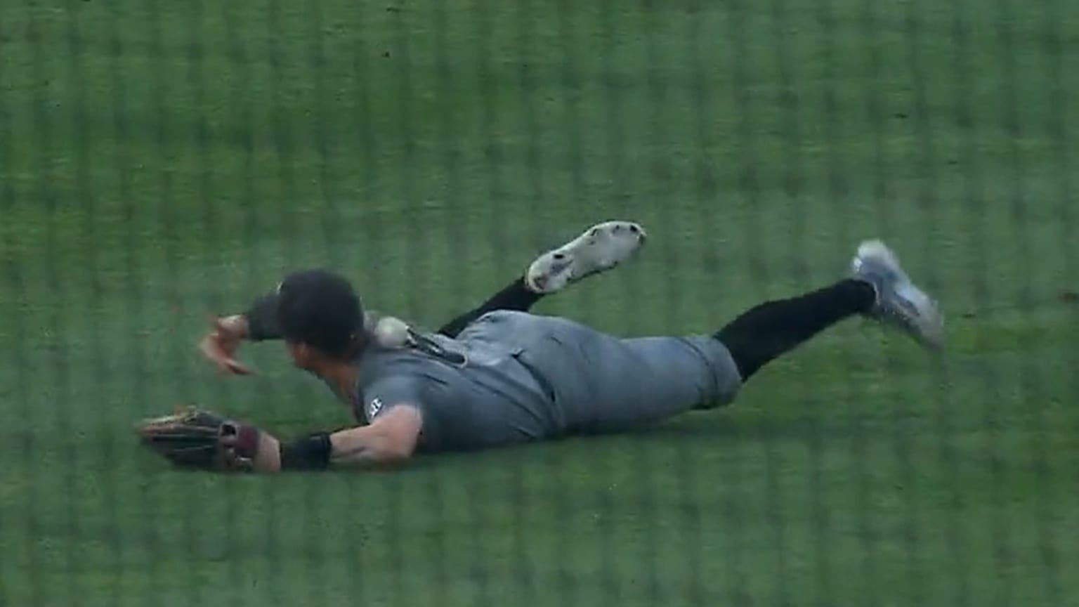 A screengrab shows a baseball rolling across an outfielder's back