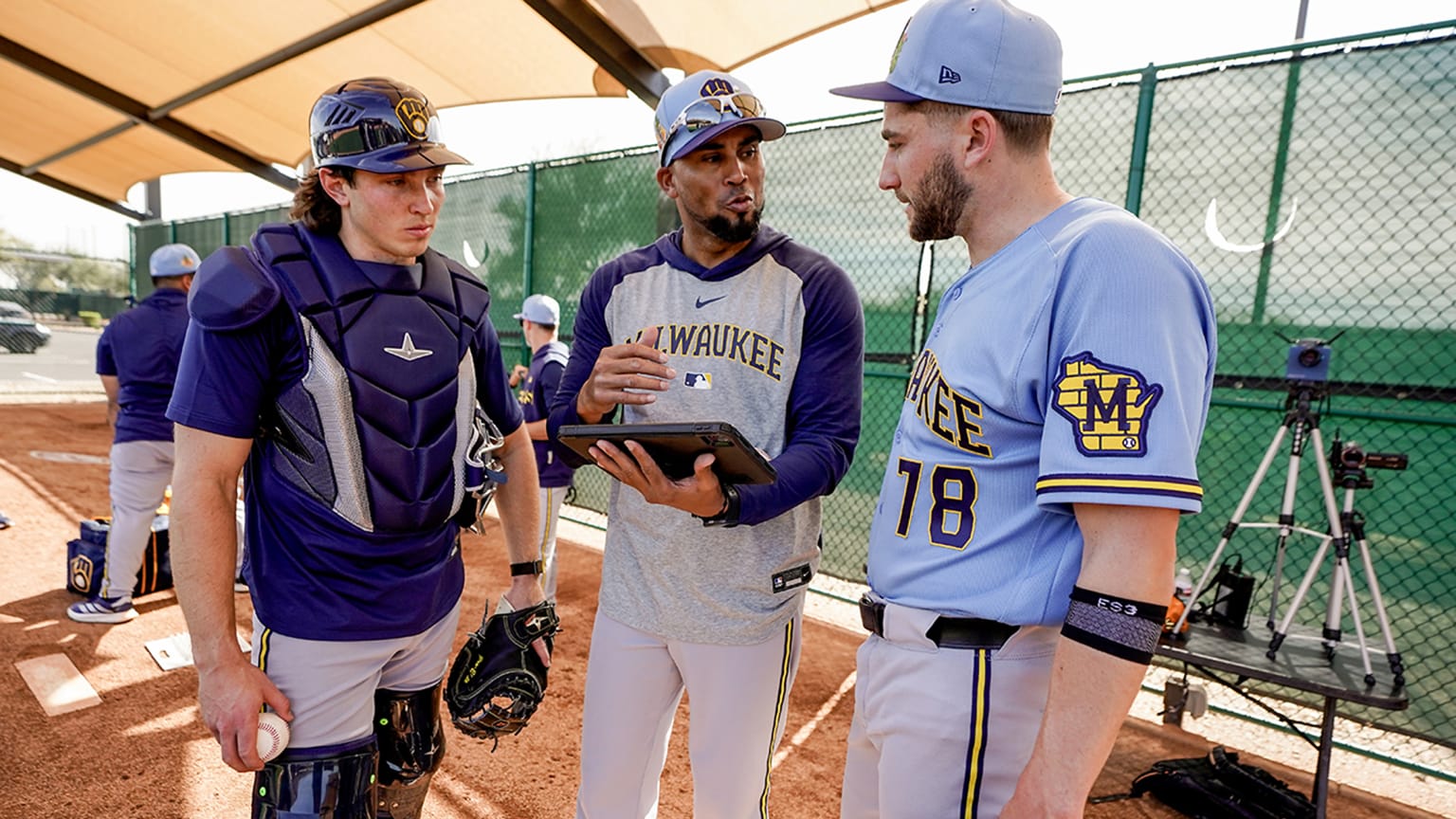 Brewers assistant pitching coach Juan Sandoval talks with two players in camp