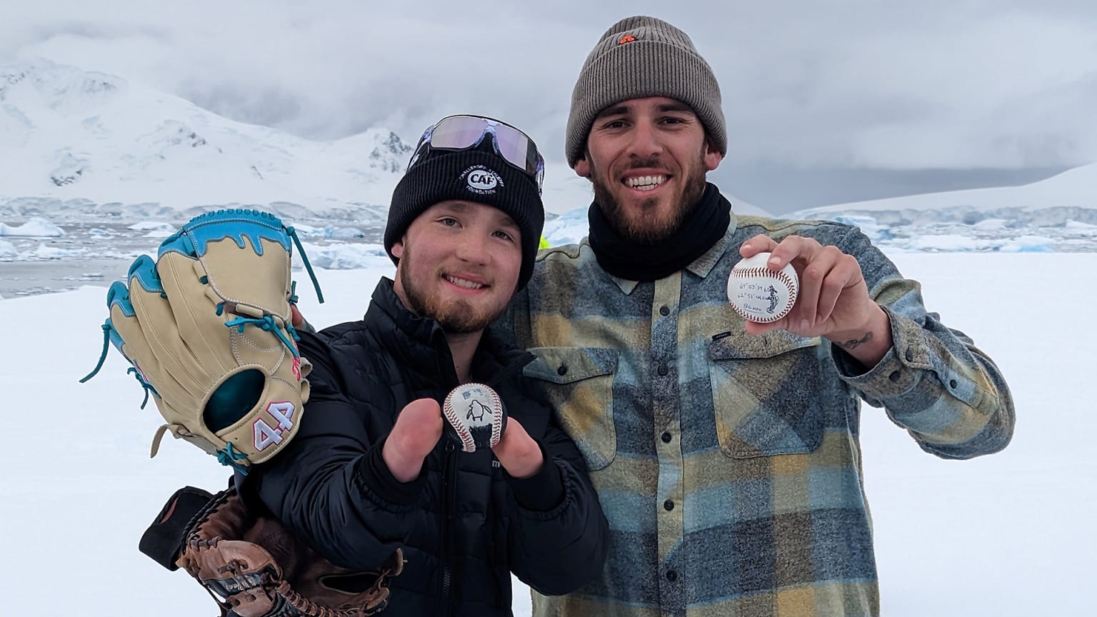 Joe Musgrove and another man show off baseballs in a snowy landscape in Antarctica