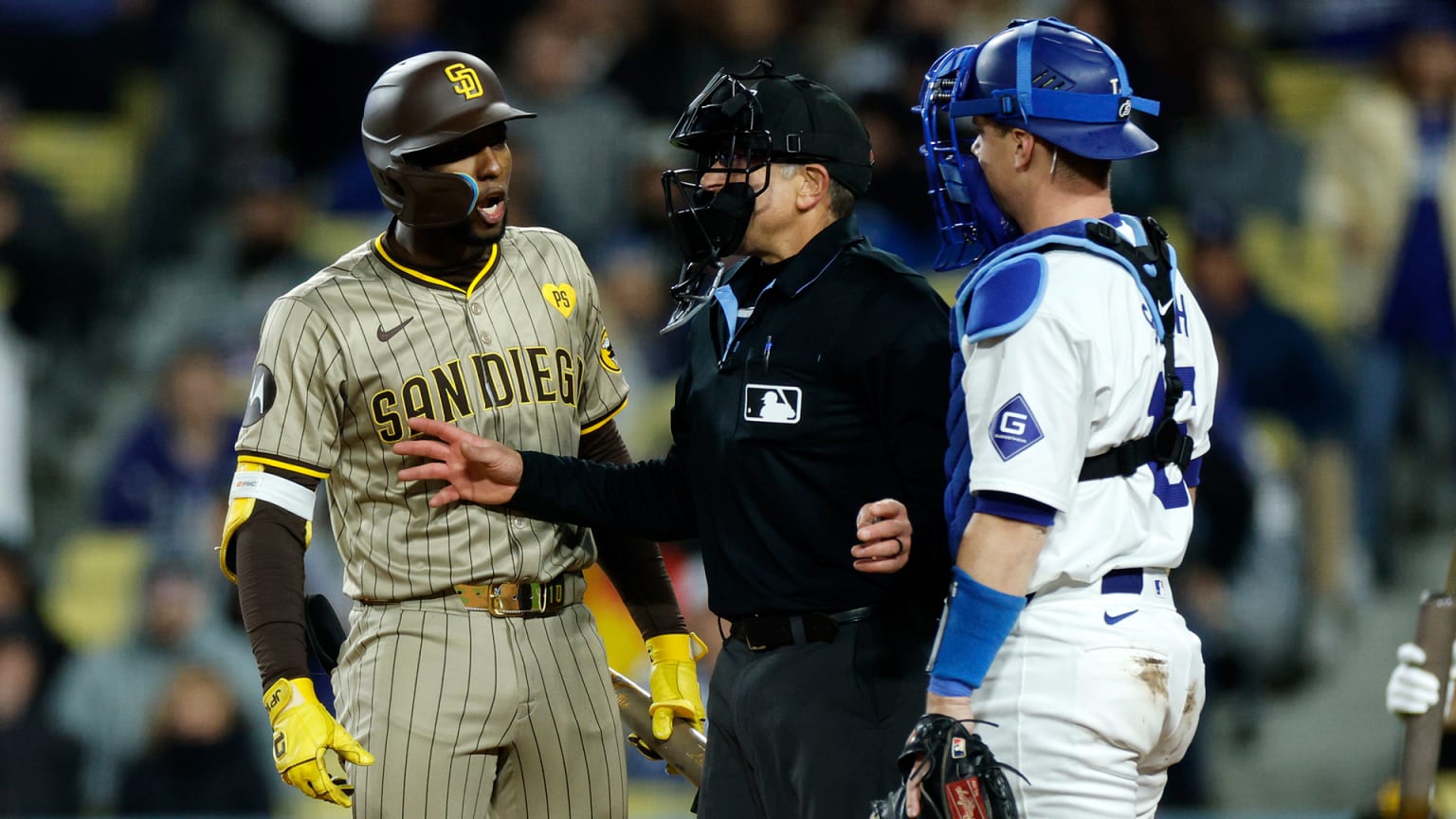 The Padres' Jurickson Profar and Dodgers' Will Smith are separated by an umpire