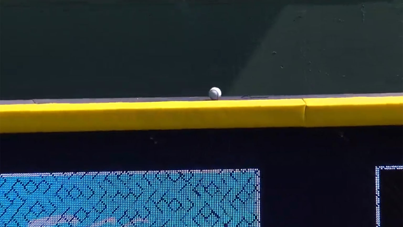 A baseball sits on top of the outfield wall