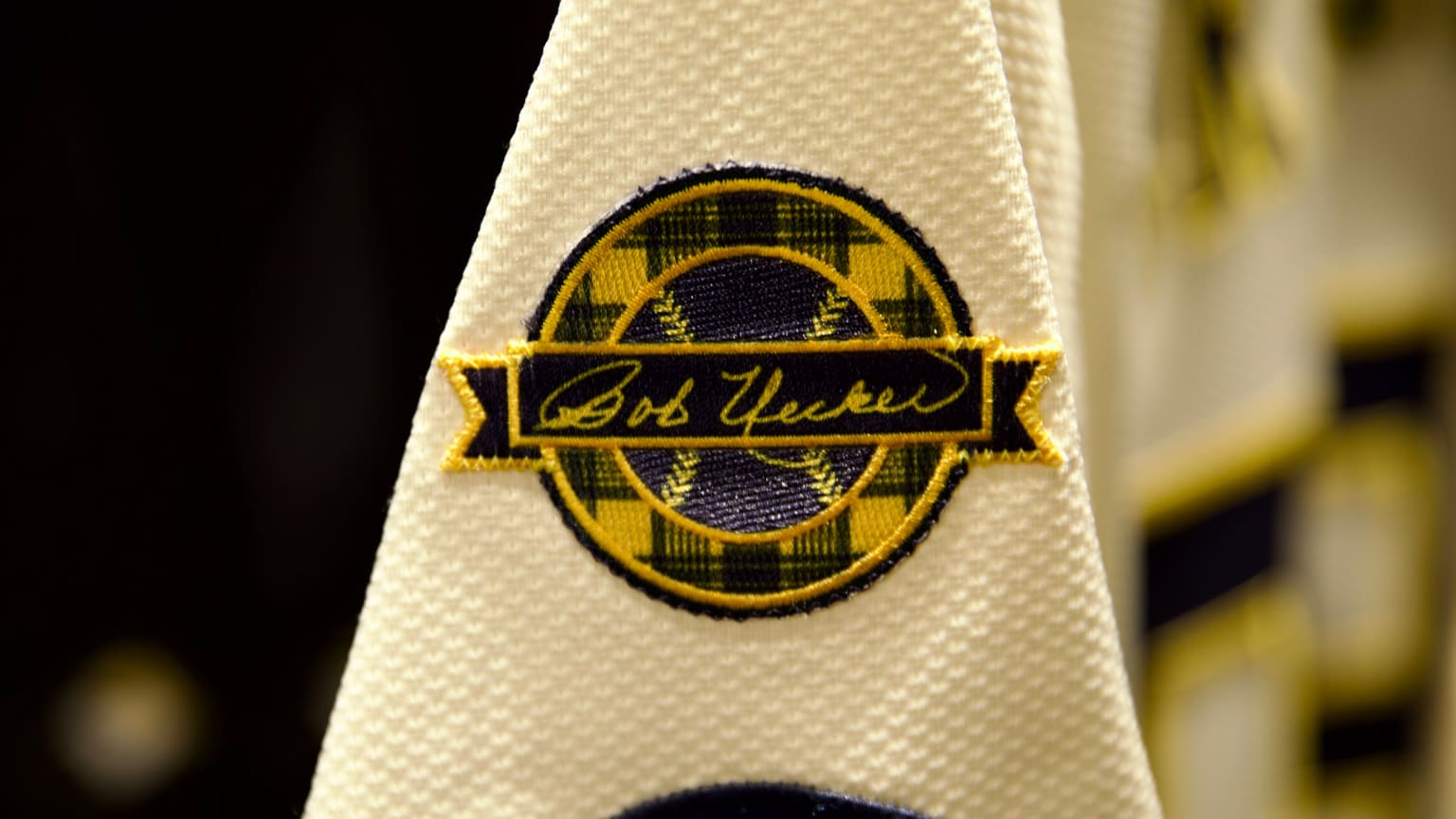 The Brewers' commemorative patch for Bob Uecker features his signature in a banner across a baseball inside a circle with a plaid pattern