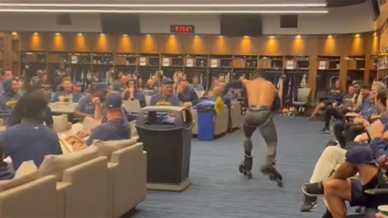 A man skating around a clubhouse with other players watching from their seats