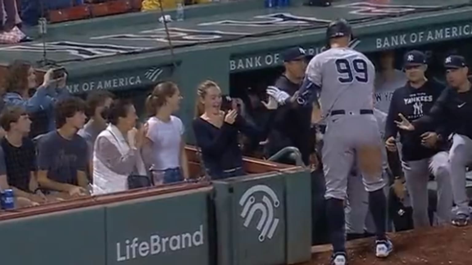 Aaron Judge high-fives a female fan who's recording on her phone as he reaches the dugout