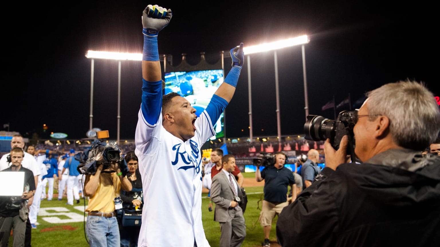 A Royals player raises his arms while celebrating on the field after a game