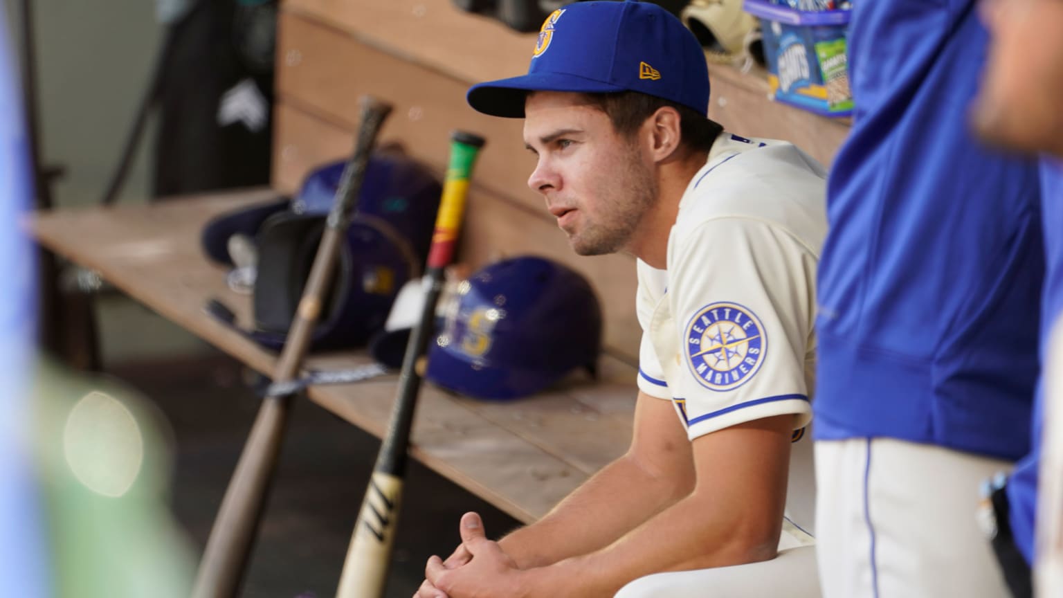 A pitcher sits in the dugout, leaning forward, a look of disbelief on his face