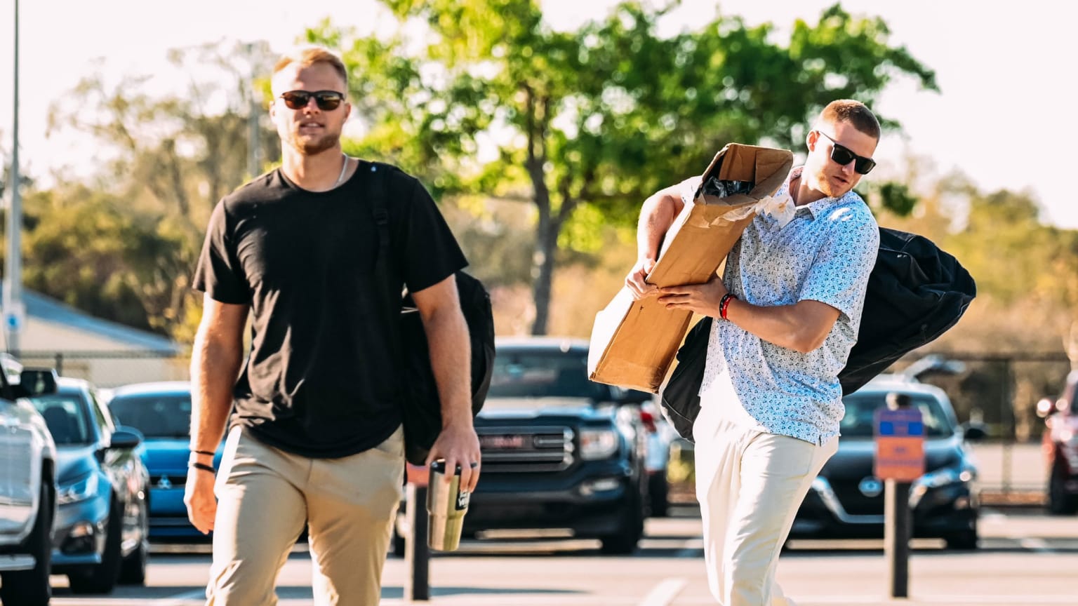 Austin Meadows and Parker Meadows walk through a parking lot together with Parker carrying golf clubs/