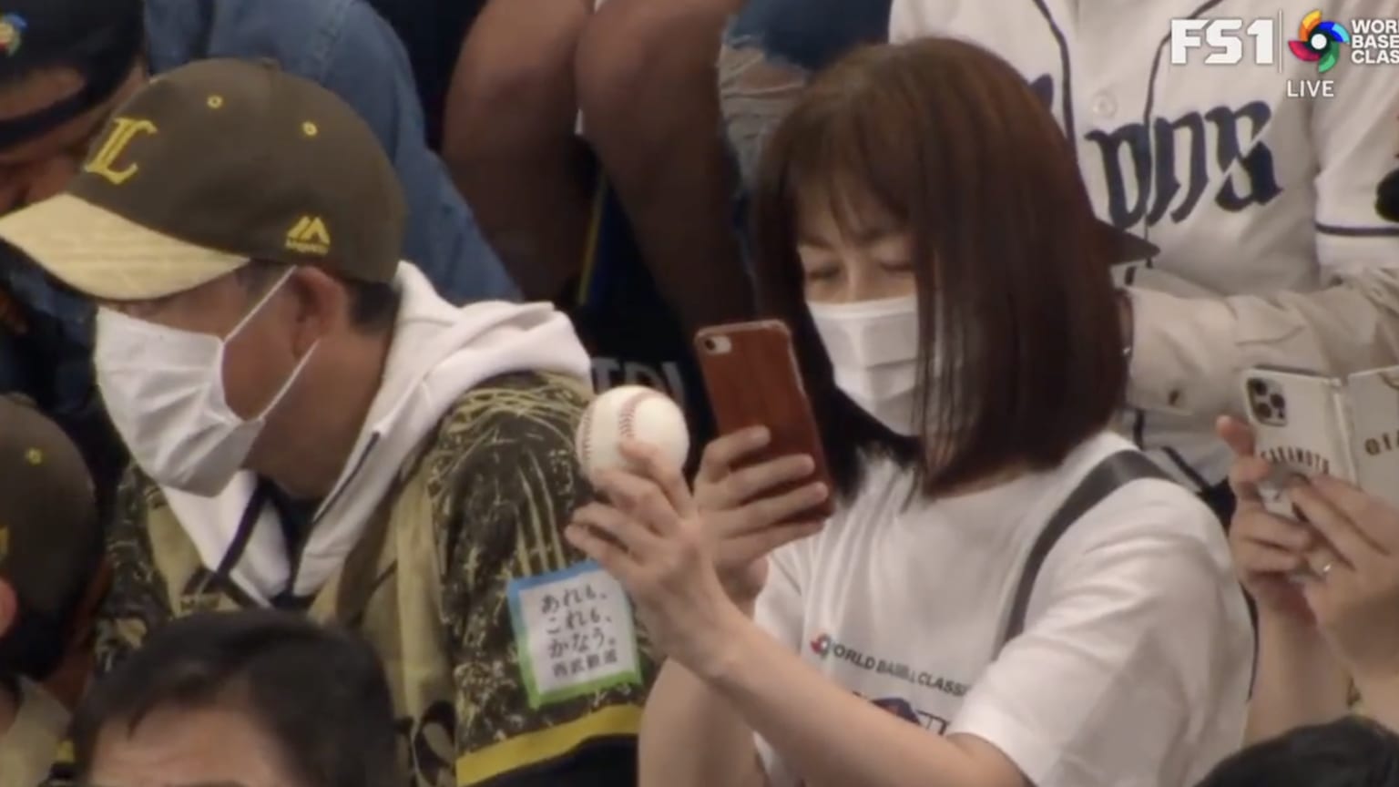 A fan takes a picture of the ball from Shohei Ohtani's first Classic homer