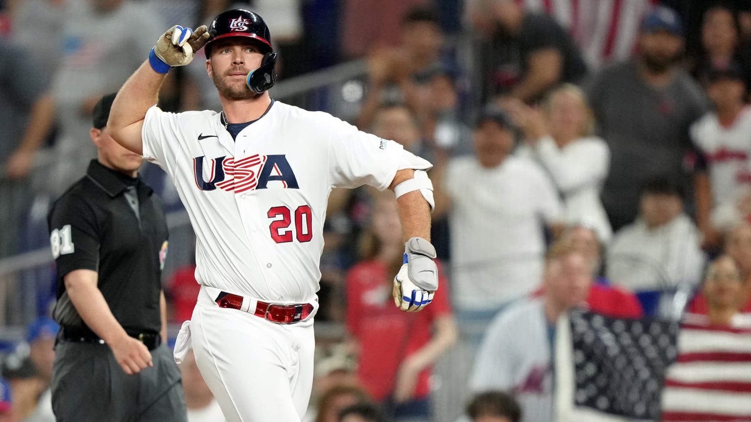 Pete Alonso in a Team USA uniform salutes in front of an umpire and fans