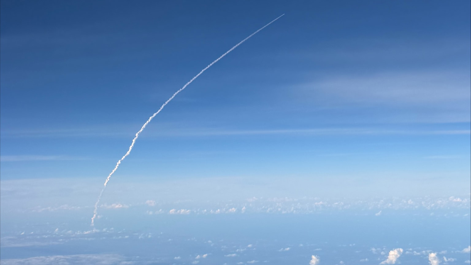 The vapor trail of Artemis II as seen from an airplane window