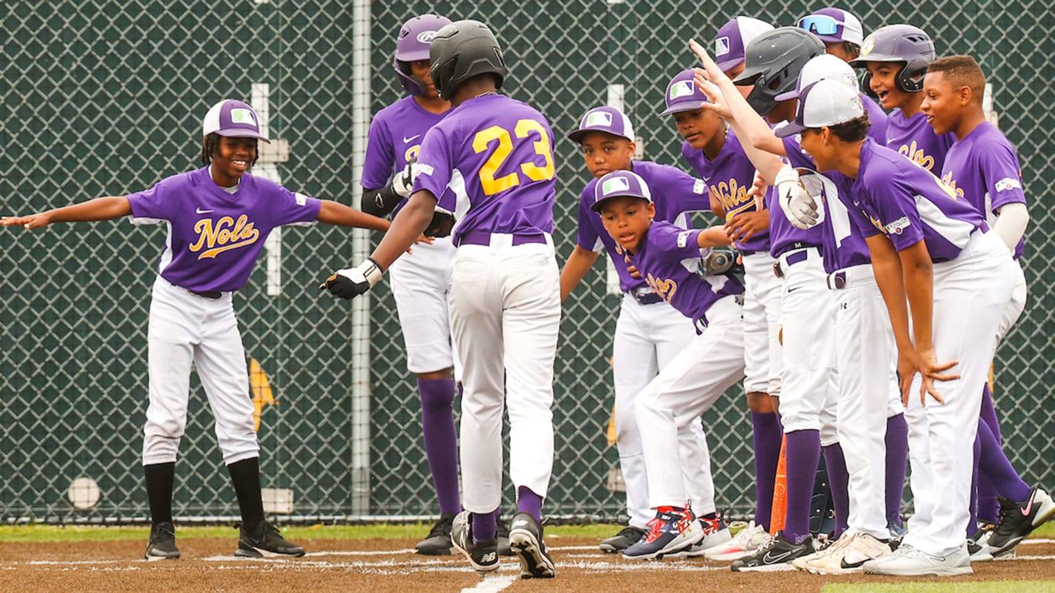 Young baseball players celebrate near home plate