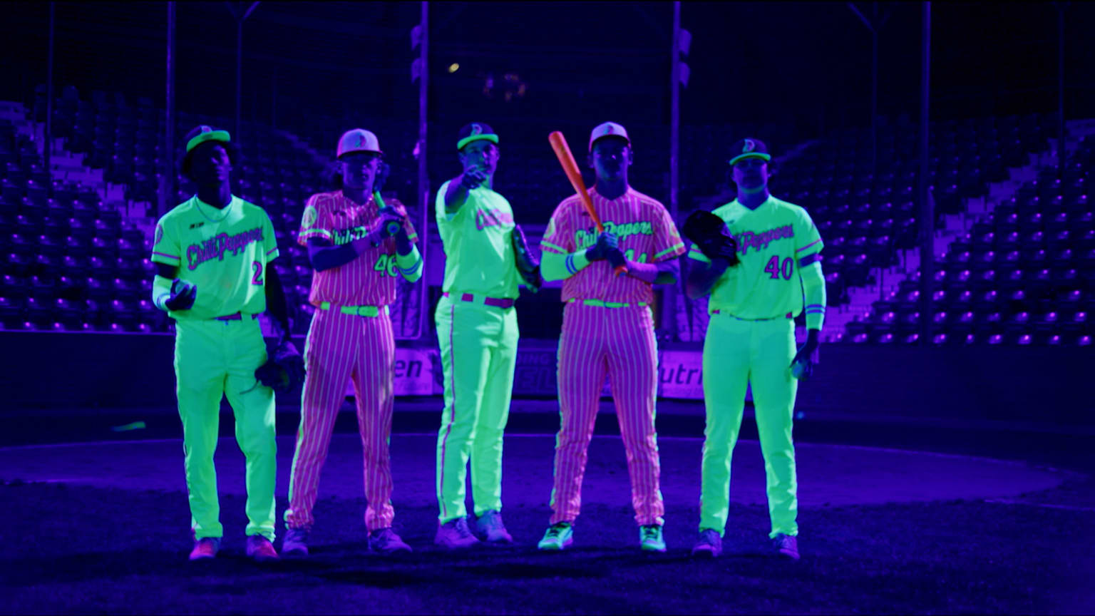 A photo of five players wearing glowing uniforms under black lights