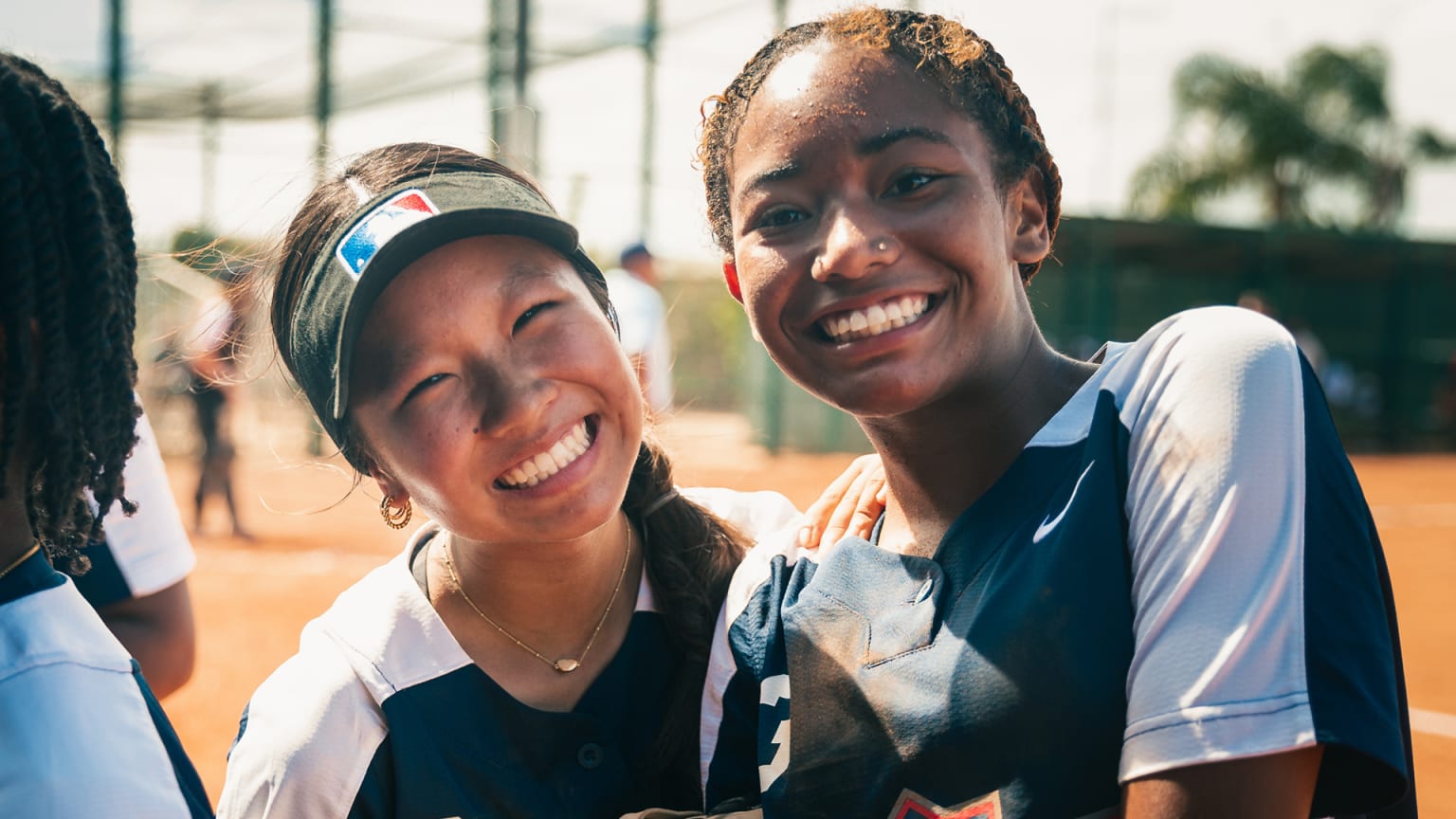 Two girls on a softball field smiling for the camera