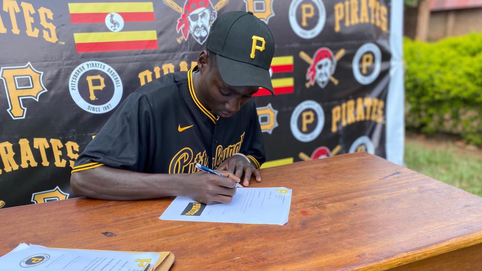 A young player in a Pirates uniform signs a contract