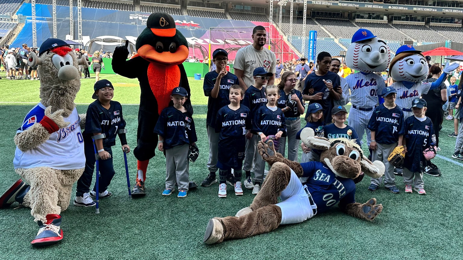 Mascots for the Braves, Orioles, Mariners and Mets pose for a group photo with young ballplayers