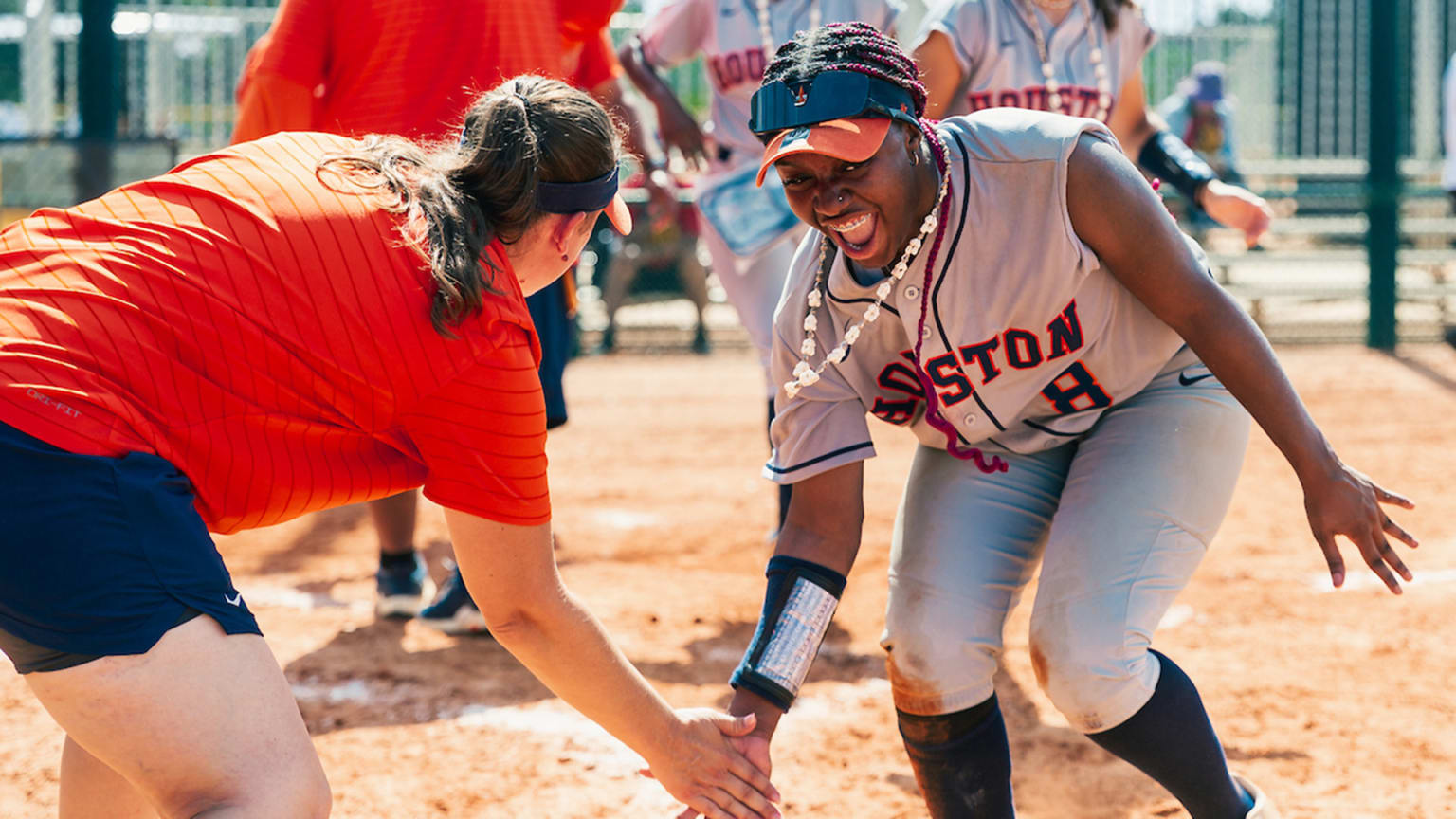 A Houston softball player reaches down for a low five with a coach