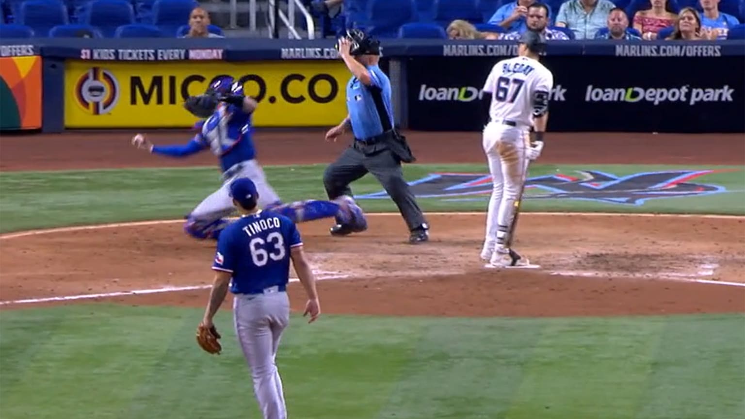 A screengrab from video of a catcher reaching out with his bare hand to catch a ball. The pitcher is in the foreground, while the umpire next to the catcher removes his mask and the batter turns to watch