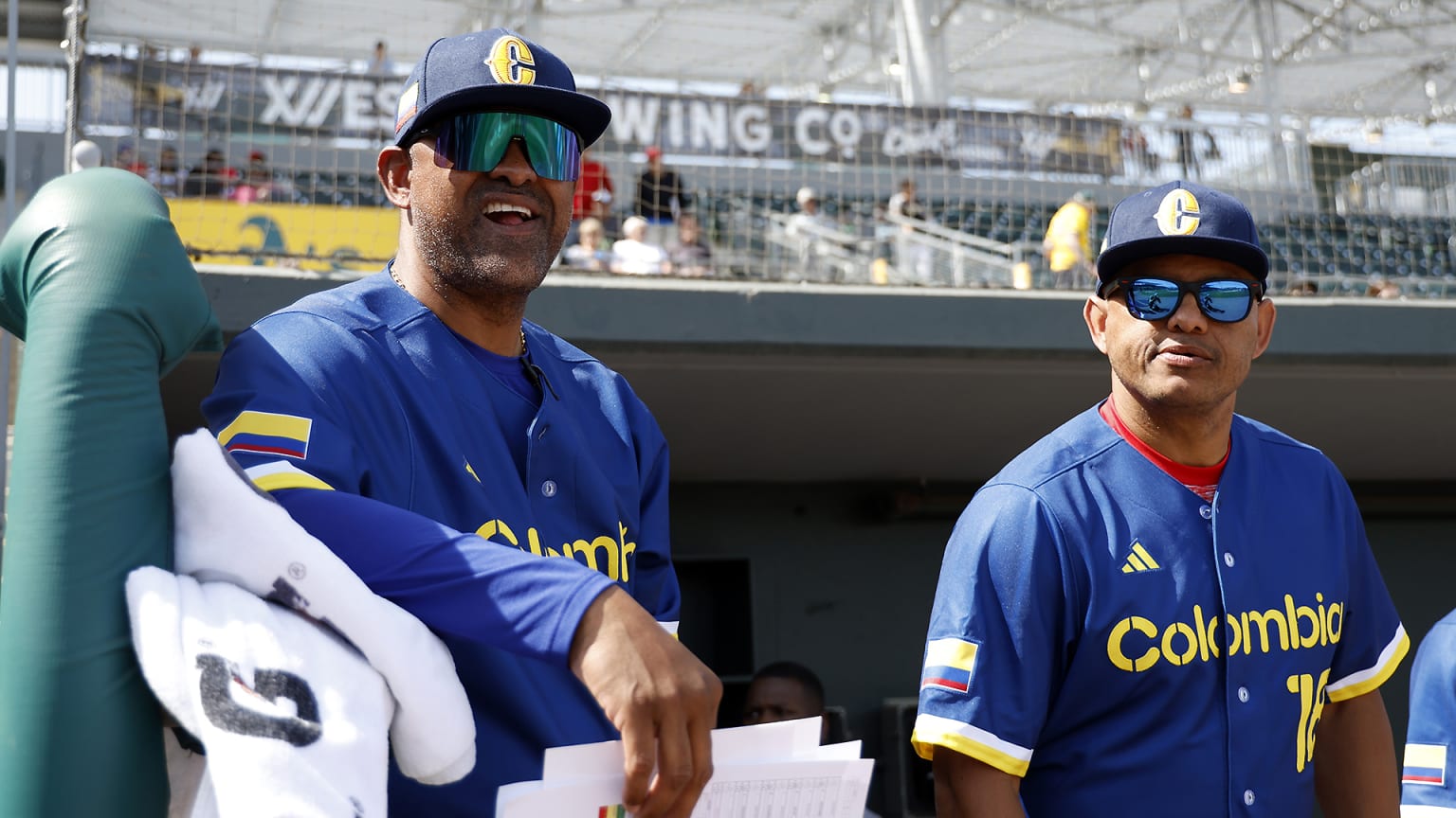 Two men in blue Colombia jerseys stand in the dugout