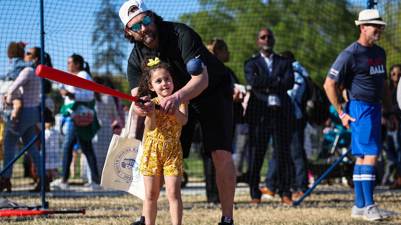 A father helps his daughter swing a bat