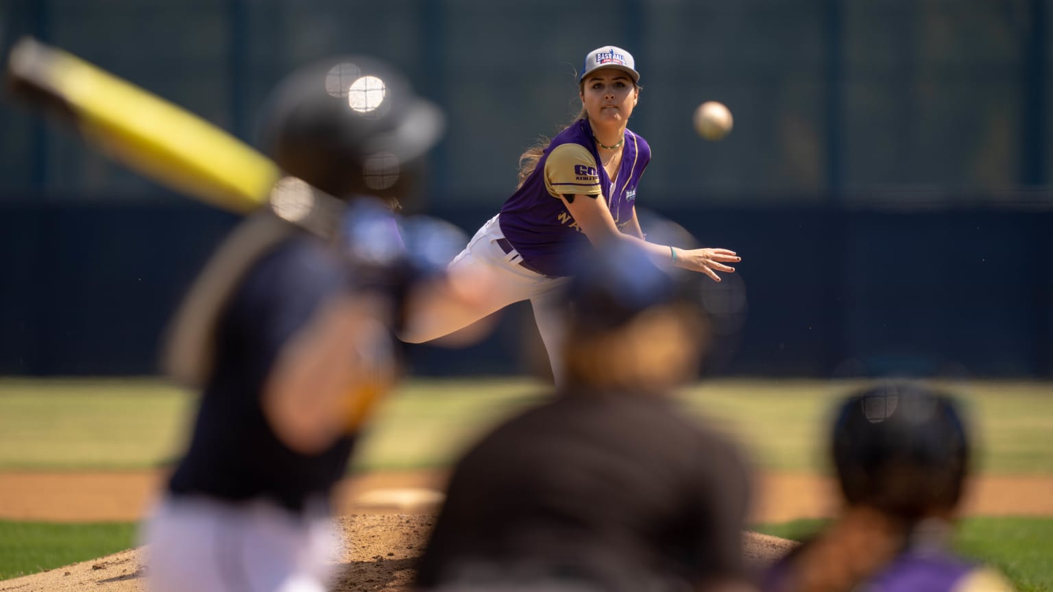 A female pitcher for the University of Washington delivers a pitch